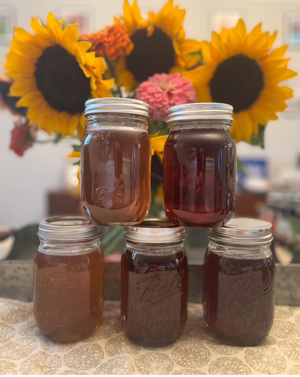 Jars of raw Wild Hearts honey, stacked in front of sunflowers